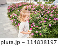 A hungry child enjoys eating ice cream outdoors. Portrait of a cute baby licking a creamy ice cream while walking in a city park, outdoor activities. 114838197
