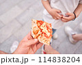 Two people eating pizza in the park. Pizza delivery concept in a cardboard box. Baked a delicious pizza Margarita 114838204