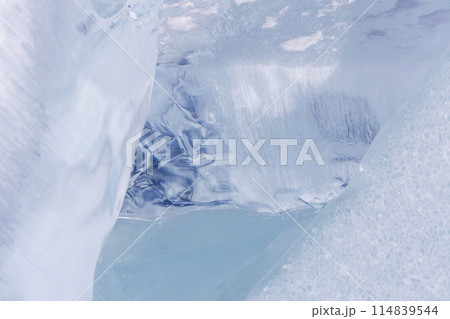 Winter natural background with fragments of blue ice and heaps of pieces of ice floes on Lake Baikal on a sunny frosty day. Abstract cold background, mock up. Harsh lifeless environment 114839544