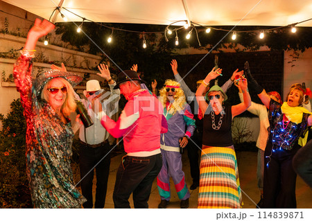 Friends having fun at a costume party under a starry sky with lights, music, dancing, and laughter Friends having fun at a costume party under a starry sky with lights, music, dancing, and laughter 114839871