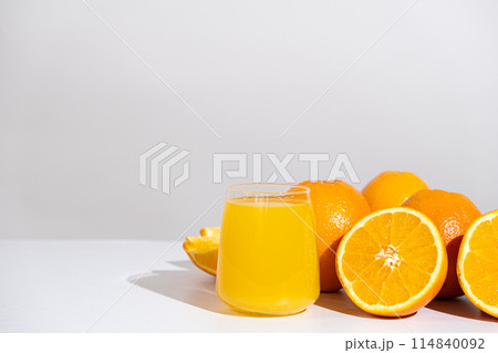 Orange juice in a glass and half a fresh orange, space for text. 114840092