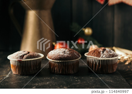 chocolate muffins with powdered sugar on top on a black background. Christmas decoration . Still life close up. Food photo chocolate muffins with powdered sugar on top on a black background. Christmas decoration . Still life close up. Food photo 114840997