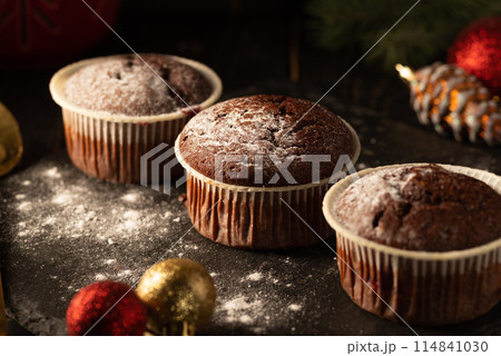 chocolate muffins with powdered sugar on top on a black background. Christmas decoration . Still life close up. Food photo. chocolate muffins with powdered sugar on top on a black background. Christmas decoration . Still life close up. Food photo. 114841030