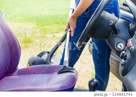 Cleaning car interior with vacuum cleaner 114841741
