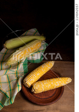 Clay plate with two cobs sweet corn on wooden background.. 114842037