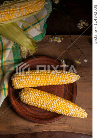 Clay plate with two cobs sweet corn on wooden background.. 114842038