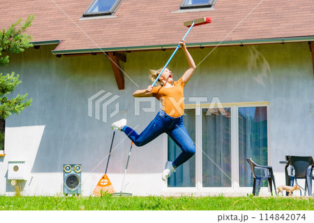 Woman with broom on backyard 114842074