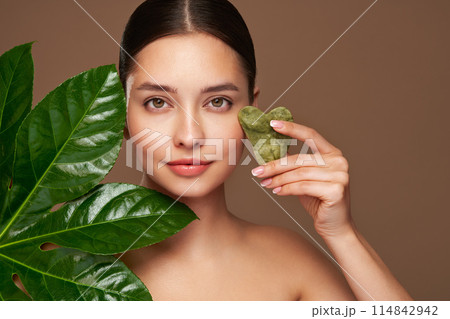 Close up woman face with green exotic leaf Close up woman face with green exotic leaf 114842942