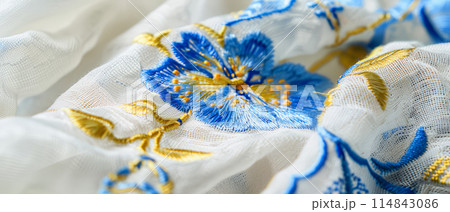 Close-up of Light Delicate Blue Embroidery on White Fabric, Highlighting Craftsmanship and Elegance 114843086