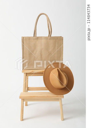 A bag with a hat on a wooden chair 114843734