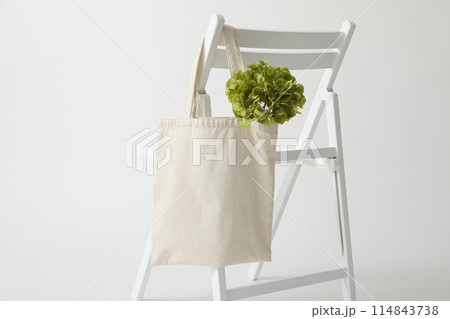 A white bag hangs on a white chair 114843738