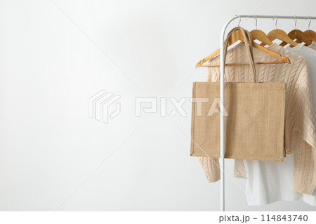 A bag hangs on a hanger with clothes 114843740
