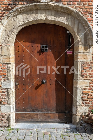 Rustic Medieval Wooden Door with Stone Archway, bathed in Sunlight, timeless ancient architecture 114843851