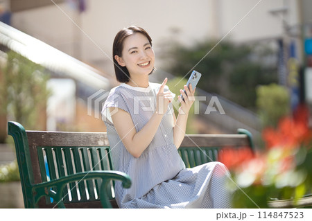 街中のベンチに座ってスマホを見る若い女性 街中のベンチに座ってスマホを見る若い女性 114847523
