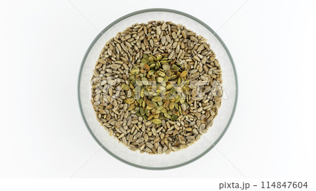 peeled sunflower seeds and pumpkin seeds in a plate on a white background, isolates peeled sunflower seeds and pumpkin seeds in a plate on a white background, isolates 114847604