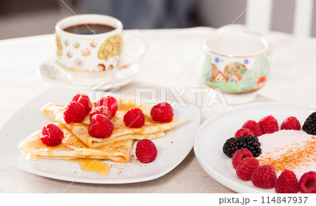 Breakfast of pancakes with fresh raspberries on table 114847937