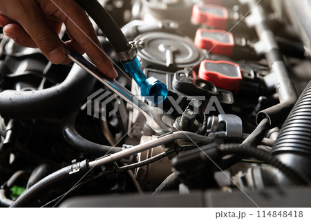 Auto mechanic man with wrench repair and maintenance to customer the engine a vehicle car hood in auto mechanics garage. 114848418