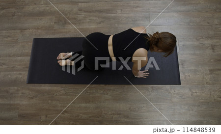 Beautiful Caucasian woman doing fitness on mat at home. Media. Top view of a girl performing exercises. 114848539