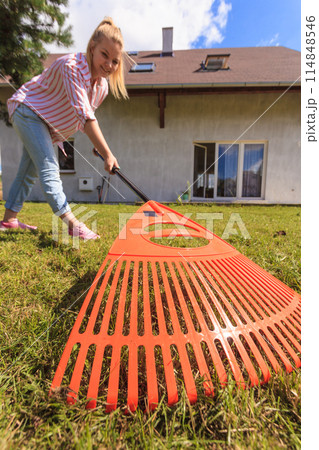 Unusual angle of woman raking leaves 114848546