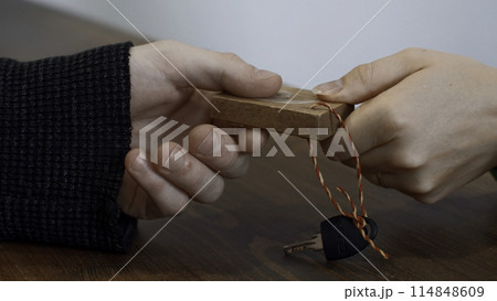 Close up of woman hand giving a key to a male hand on wooden desk background. Media. Taking a key at the fitness club reception. Close up of woman hand giving a key to a male hand on wooden desk background. Media. Taking a key at the fitness club reception. 114848609
