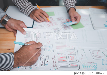 UX or UI designers designing on their smartphone application layout prototype project. UX or UI designers designing on their smartphone application layout prototype project. 114848677