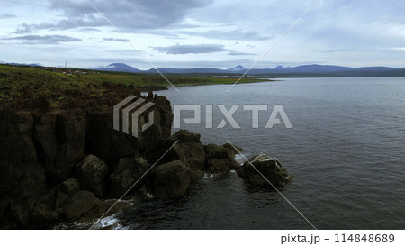 Bird eye view of calm ocean and stone rock cliffs at Oregon coast. Clip. Aerial of the ocean water surface and green meadows. Bird eye view of calm ocean and stone rock cliffs at Oregon coast. Clip. Aerial of the ocean water surface and green meadows. 114848689