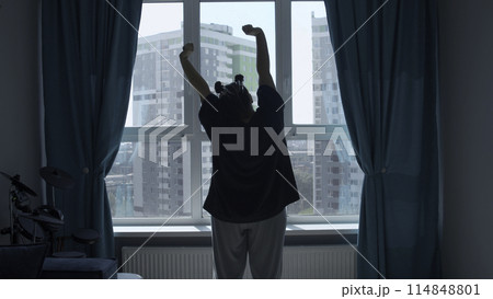Relaxed lady stretching hands in the morning at home, back view. Media. Woman raising arms up enjoying new day after waking up. Relaxed lady stretching hands in the morning at home, back view. Media. Woman raising arms up enjoying new day after waking up. 114848801