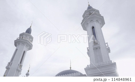 A white and gray historical mosque. Scene. Religious building with minarets on cloudy sky background. A white and gray historical mosque. Scene. Religious building with minarets on cloudy sky background. 114848961