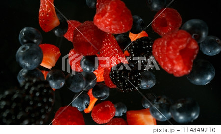 Fresh pieces of berries falling into water, top down view, black background 114849210