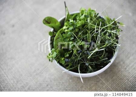 Green salad in a cup on a burlap cloth. Herbal salad on a yellow background. 114849415