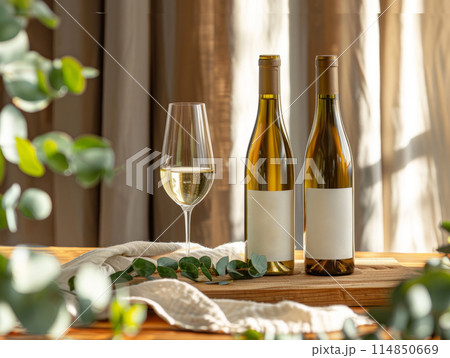 Beautiful eucalyptus and bottle of wine on table against light background 114850669