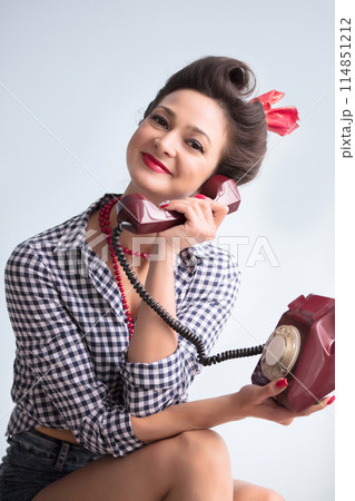 Woman in the style of the fifties. Beautiful retro girl with an old telephone. Woman in the style of the fifties. Beautiful retro girl with an old telephone. 114851212