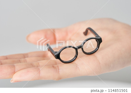 女性の手のひらに乗せられたメガネの模型 女性の手のひらに乗せられたメガネの模型 114851501
