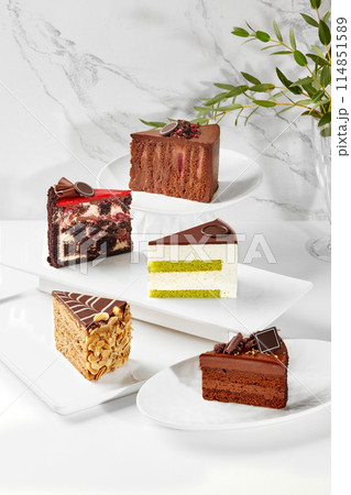 Variety of exquisite cake slices on plates against marble backdrop Variety of exquisite cake slices on plates against marble backdrop 114851589