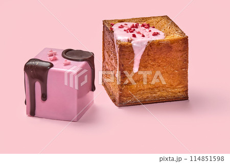 Two cube croissants with chocolate and berry glaze against pink background 114851598