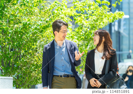 街路樹のあるオフィス街を歩く笑顔のビジネスマン男女 114851891