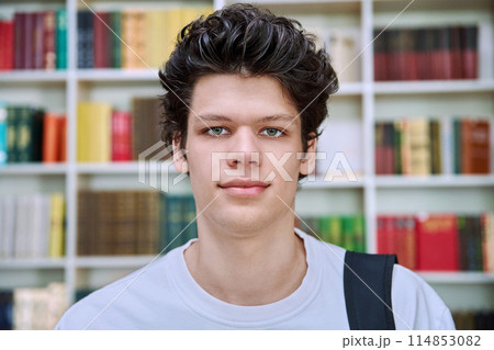 Headshot portrait of college student guy with crossed arms inside library of educational building Headshot portrait of college student guy with crossed arms inside library of educational building 114853082