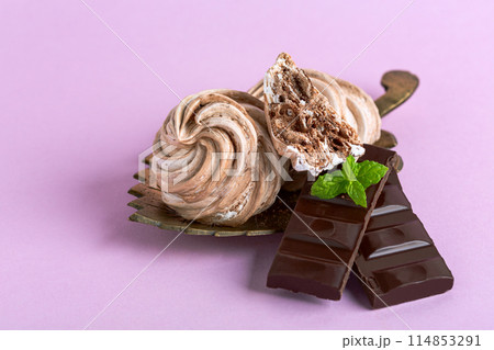 Meringues with dark chocolate close up. 114853291