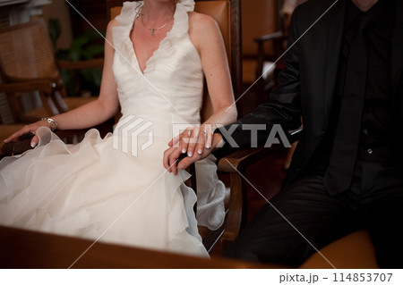 A beautiful moment captured as a Bride and Groom hold hands in a romantic wedding ceremony A beautiful moment captured as a Bride and Groom hold hands in a romantic wedding ceremony 114853707