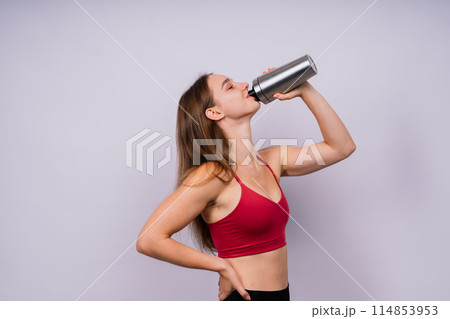 Sporty muscular woman drinking water, isolated against white background Sporty muscular woman drinking water, isolated against white background 114853953