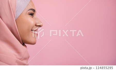 Cheerful face. Happy expression. Side view portrait of optimistic smiling woman in headscarf isolated on pink empty space background. 114855295