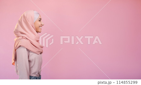 Muslim beauty. Friendly expression. Optimistic attitude. Profile of cheerful woman in hijab isolated on pastel pink empty space background. 114855299