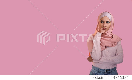 Pensive expression. Idea contemplation. Doubtful thoughtful woman in hijab thinking on problem isolated on pink empty space advertising background. Pensive expression. Idea contemplation. Doubtful thoughtful woman in hijab thinking on problem isolated on pink empty space advertising background. 114855324