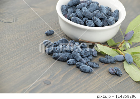 White bowl filled with Honeyberry haskap berries on wooden table 114859296