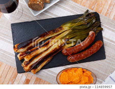 Grilled sausage and delicious calsot served on plate with sauce, traditional dish of Catalonia Grilled sausage and delicious calsot served on plate with sauce, traditional dish of Catalonia 114859957
