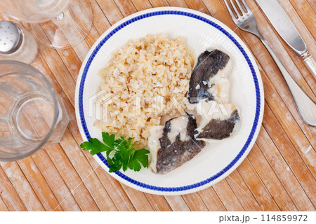 Tender meat of baked cod fillet is garnished with boiled basmati rice. 114859972