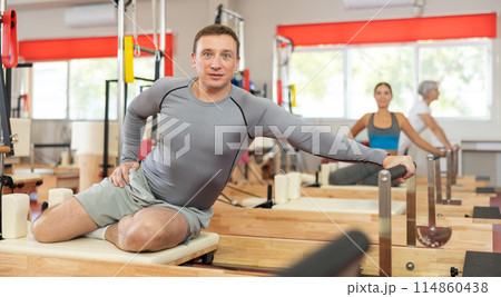 Adult man doing stretching on pilates machine Adult man doing stretching on pilates machine 114860438