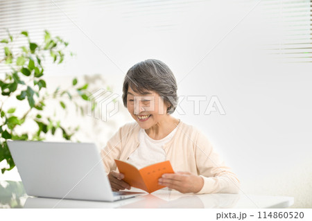 年金手帳を見ながらパソコンを使うシニア女性 終活 年金手帳を見ながらパソコンを使うシニア女性 終活 114860520