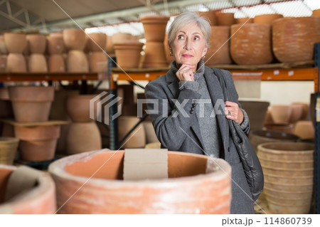 Senior woman looking for pots for growing plants in greenhouse 114860739