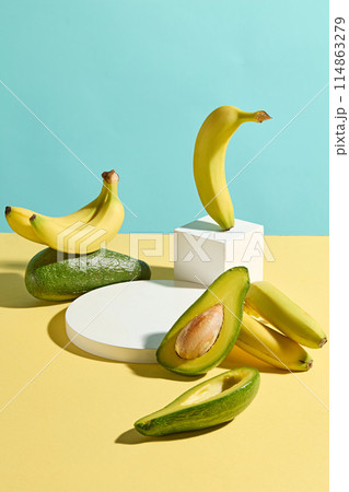 Unique template photo with high angle shot for designing, the table of yellow color featuring fresh avocado, banana and a round blank platform in center. Empty space for displaying and adding text 114863279